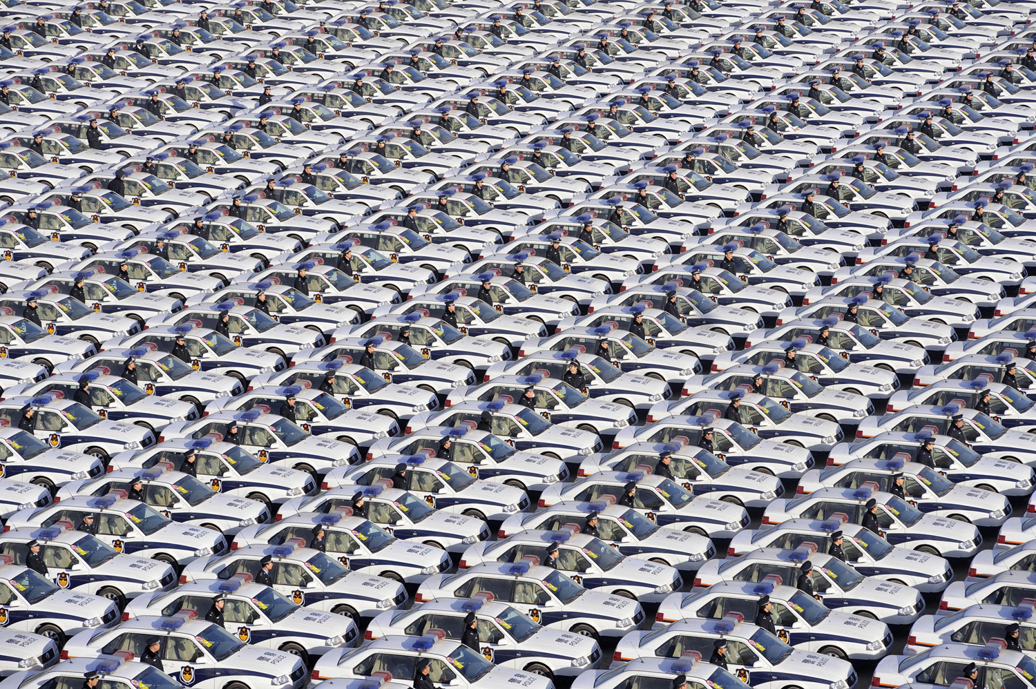 стотици полицаи стоят редом до чисто нови полицейски автомобили, предоставяни от местната власт, за да се гарантира обществената сигурност през новогодишните празници по време на церемония по предаването им в Тайюан, провинция Шанси, на 30 декември, 2009
