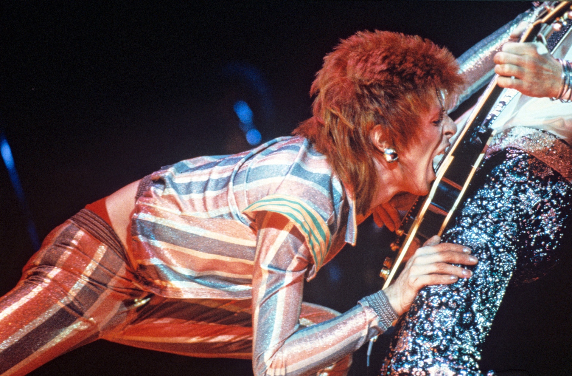Бауи хапе струните на китариста си, Мик Ронсън, през 1973 г. Снимка: Rex Features